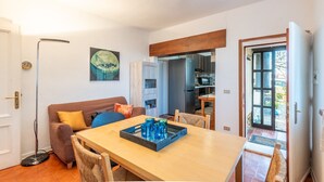 A compact living space with a dining table, a sofa, and a kitchen area visible through an open door.