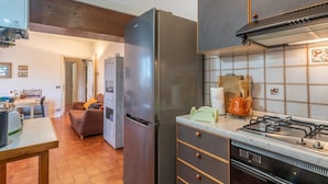 A kitchen with a stainless steel refrigerator, a gas stove, and a tiled backsplash.