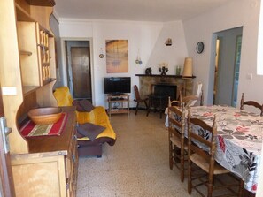 Una sala de estar con sofá, televisión, chimenea, mesa de comedor y estanterías de madera.