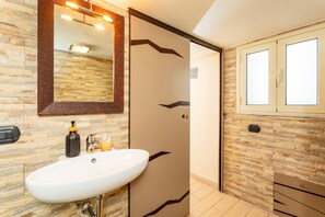 Ein Badezimmer mit Waschbecken, Spiegel, Handtuchspender und Fenster.