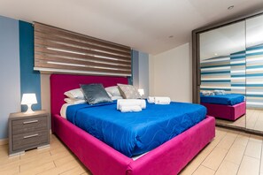 Ein modernes Schlafzimmer mit einem großen Bett, einem Nachttisch, einem Spiegel und einer Schiebetür.