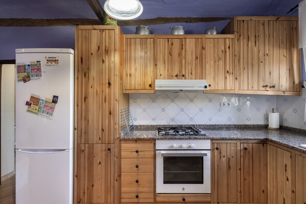 A kitchen with wooden cabinets, a white refrigerator, a stove, and a tiled backsplash.