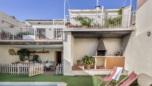 Een woonhuis met een zwembad, buitenzitplaatsen, een barbecuehoek en een balkon met bloempotten.