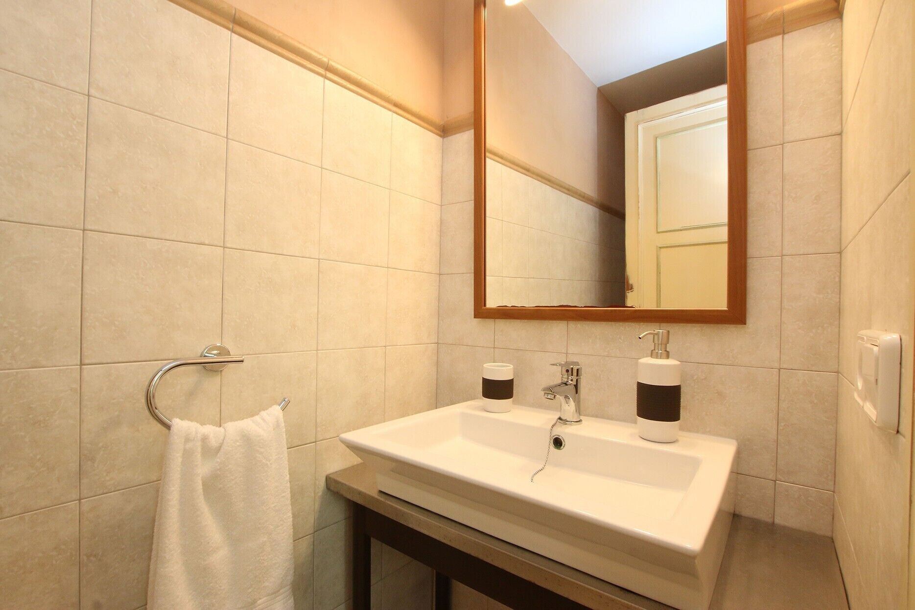 A bathroom with a white sink, a mirror, and a towel rack.