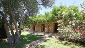 A stone building with a paved pathway leading to it, surrounded by greenery and flowering plants. - Country House 'Ca Na Barbara' with Private Pool, Wi-Fi, and Air Conditioning (Santanyí)