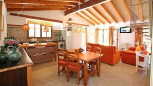 A spacious living area with a dining table, chairs, a sofa, and a television. - Country House 'Ca Na Barbara' with Private Pool, Wi-Fi, and Air Conditioning (Santanyí)