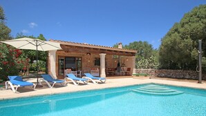 A pool area with lounge chairs, a covered patio, and a stone building. - Country House 'Ca Na Barbara' with Private Pool, Wi-Fi, and Air Conditioning (Santanyí)