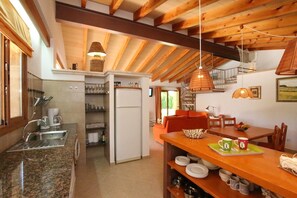 A kitchen with a refrigerator, sink, and wooden ceiling beams.