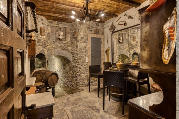 A stone-walled room with a fireplace, wooden furniture, and a mirror.