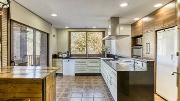 A modern kitchen with a wooden island, stainless steel appliances, and a view of the outdoors.