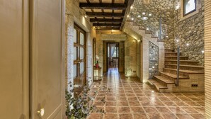A hallway with stone walls, wooden beams, and a staircase.