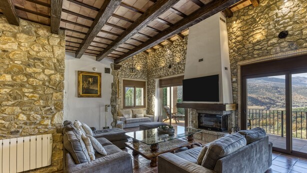 A spacious living area with stone walls, a fireplace, and a large TV.