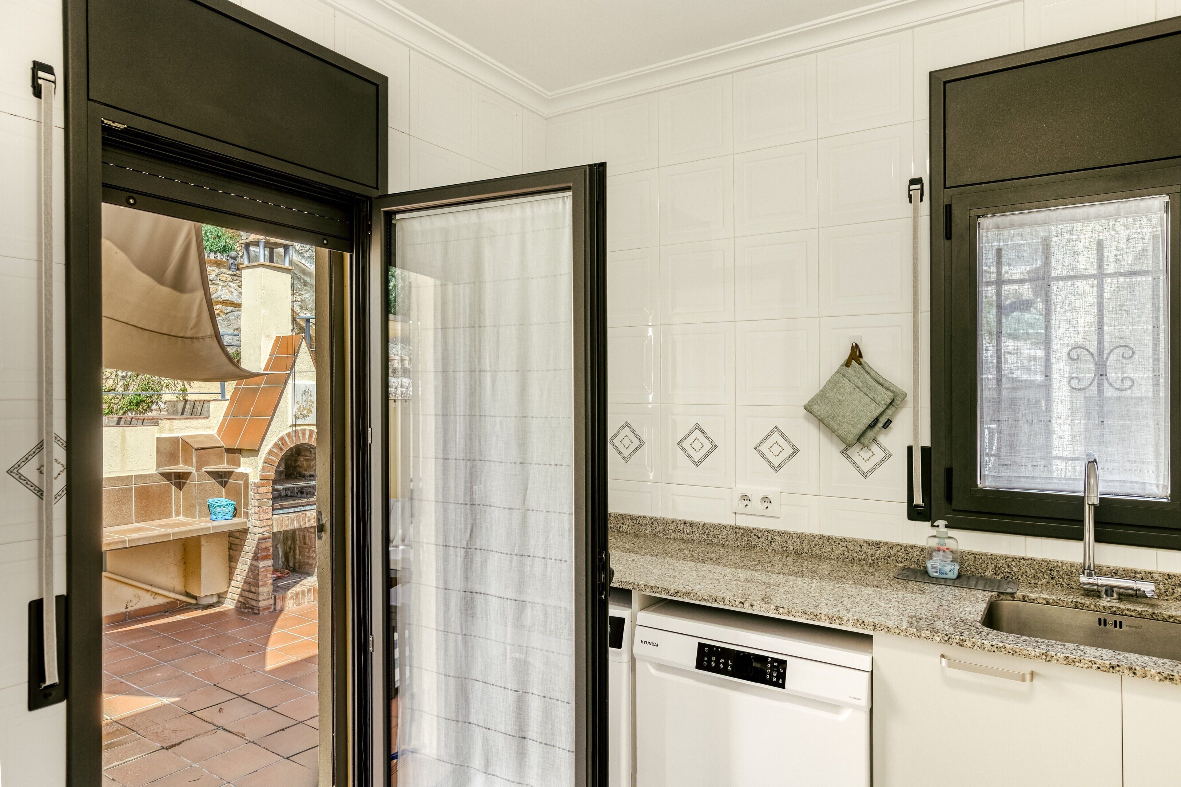 Une cuisine équipée d’un lave-vaisselle, une fenêtre avec vue et une porte donnant sur un espace extérieur.