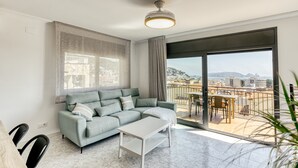 Uma sala de estar moderna com sofá, mesa de centro e varanda com vista para a cidade.