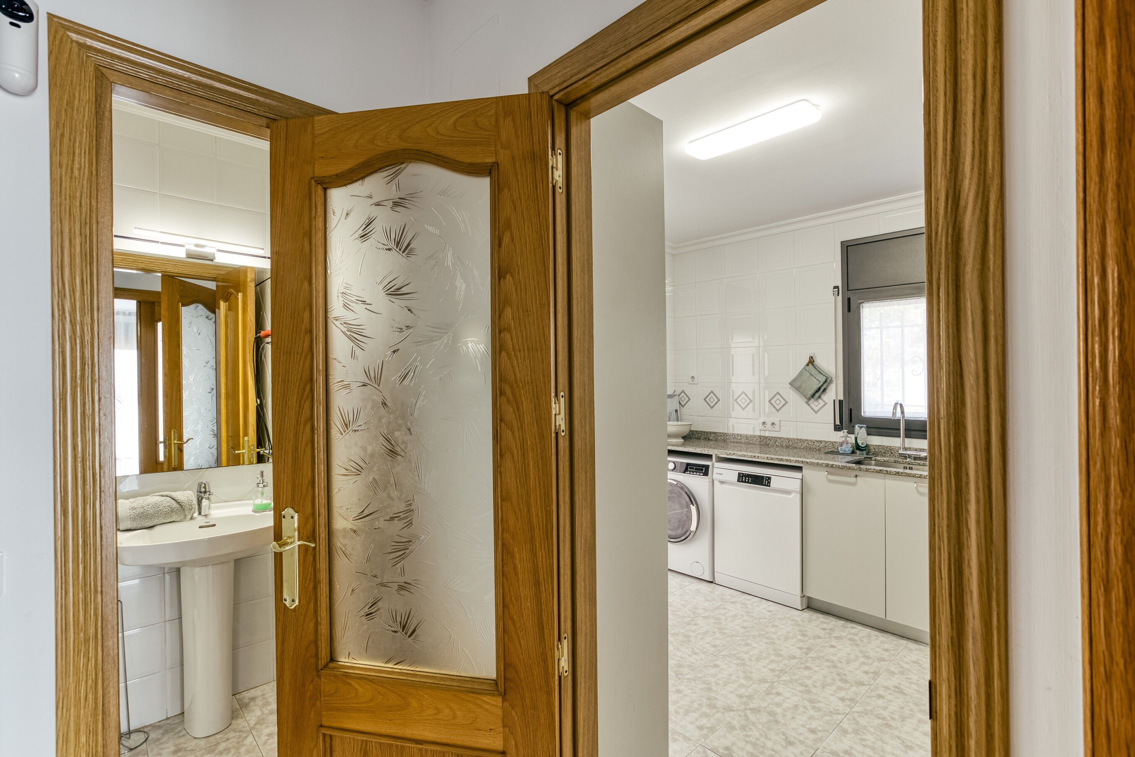 A modern kitchen with a washing machine, a sink, and a mirror.
