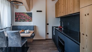 Eine moderne Küche mit Holzschränken, einer schwarzen Arbeitsplatte und einem Essbereich mit einer Bank und Stühlen.