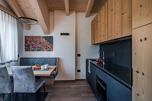 Una cucina moderna con mobili in legno, un piano di lavoro nero e un'area pranzo con una panca e sedie.