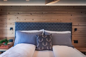 Un letto rifatto con una testiera trapuntata, due cuscini e un cuscino decorativo con motivi a corna.