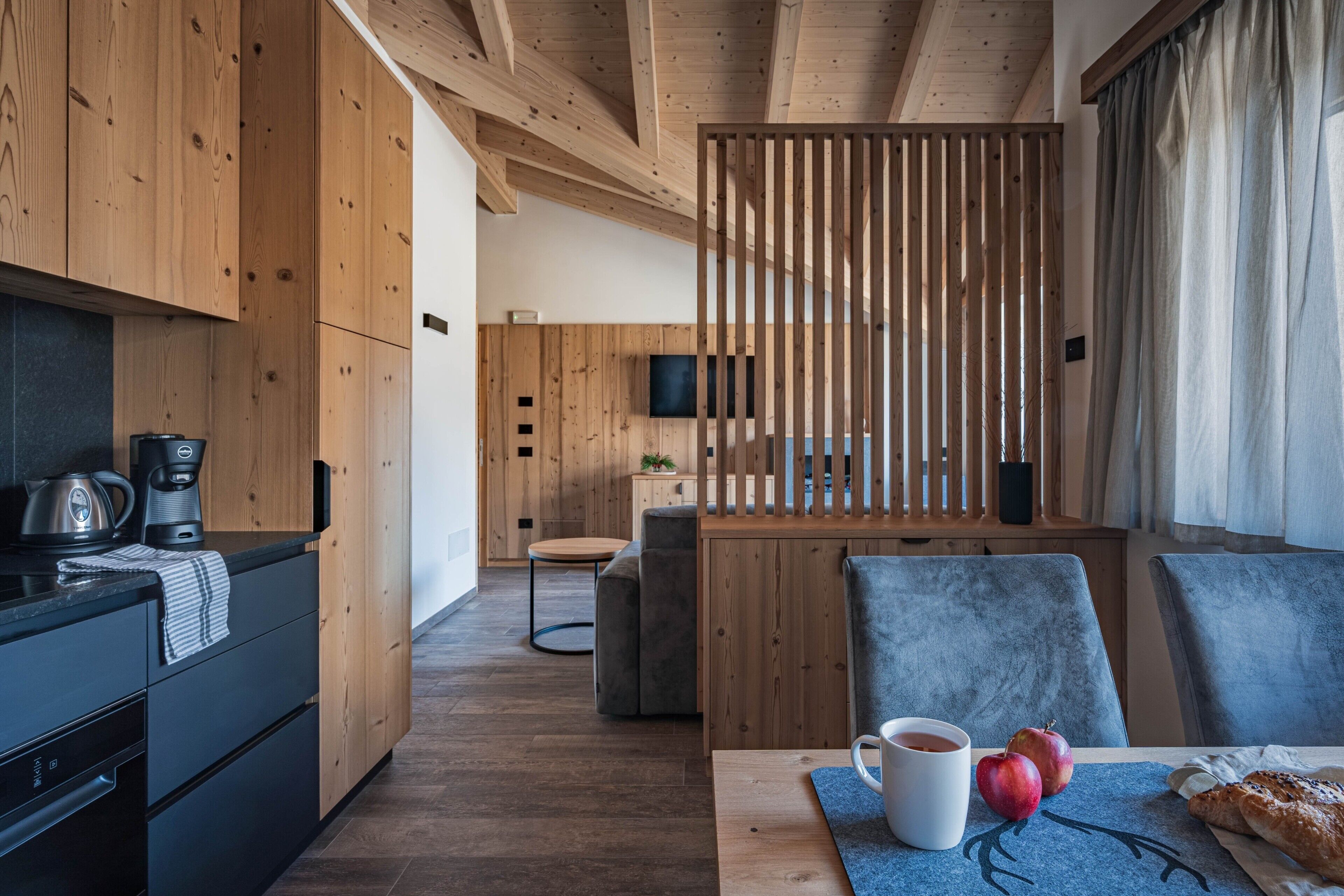 Eine moderne Küche mit Holzschränken, einer Kaffeemaschine und einer Essecke mit Tisch für zwei Personen.