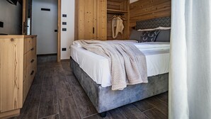 A bedroom with a bed, wooden wardrobe, and a television on a stand. - Apartment 'Rododendro' with Mountain View, Wi-Fi and Air Conditioning (Cavedago)