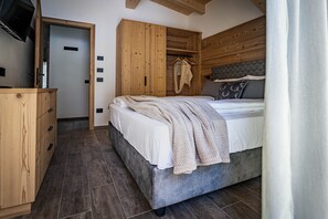 A bedroom with a bed, wooden wardrobe, and a television on a stand. - Apartment 'Rododendro' with Mountain View, Wi-Fi and Air Conditioning (Cavedago)