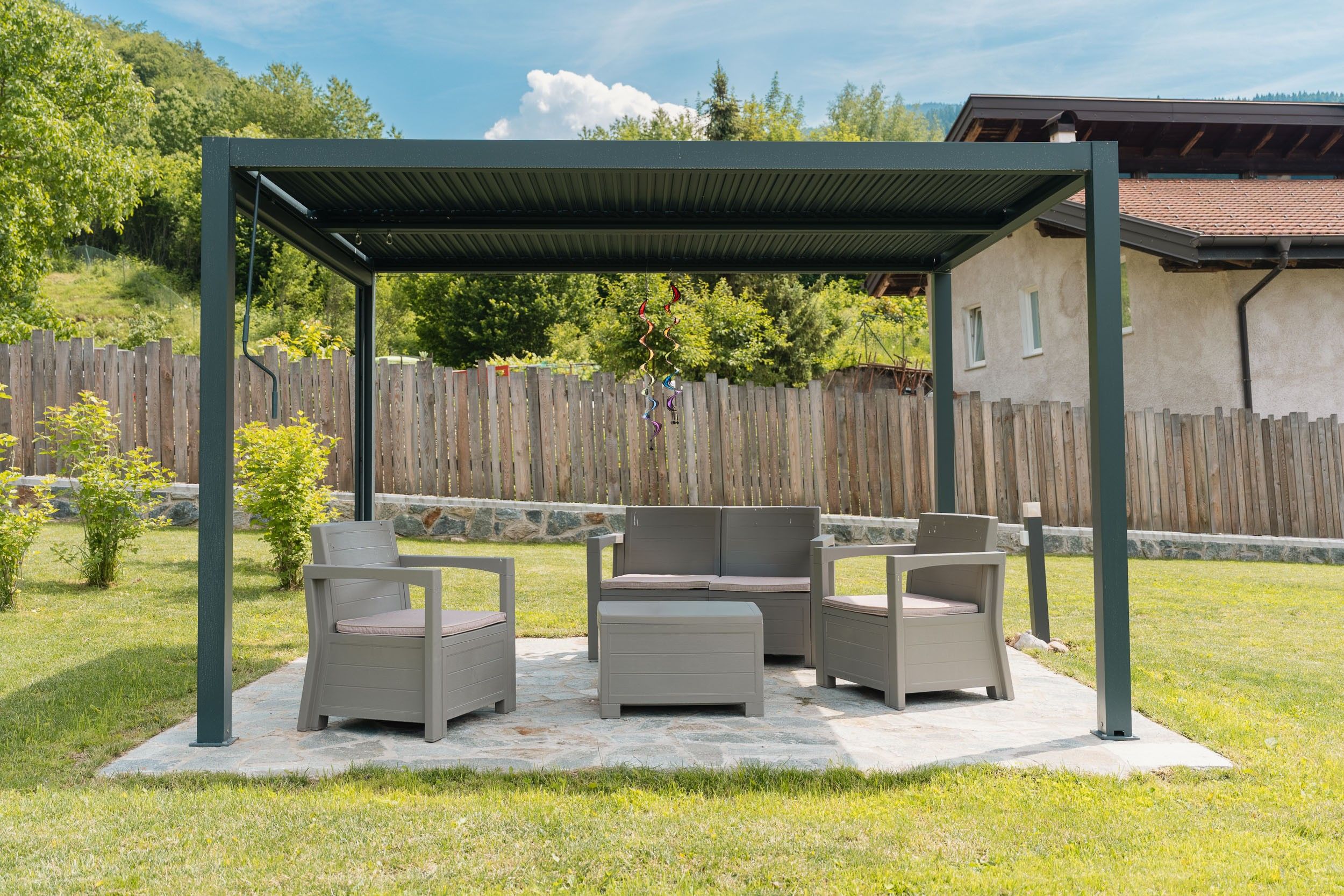 An outdoor patio area with a covered seating arrangement and a stone floor.