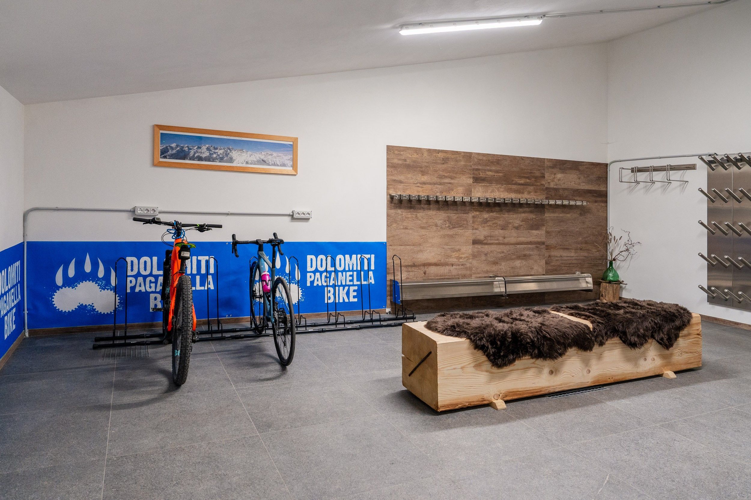 A room with a bike rack, a wooden bench, and a wall-mounted bike stand.