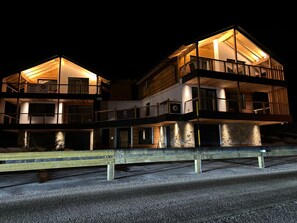 Ein mehrstöckiges Gebäude mit Balkonen, einer Stein-Fassade und einer Holzterrasse.