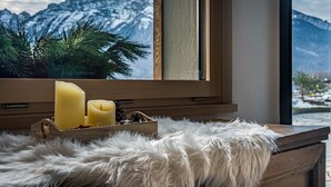 A wooden dresser with a fur throw, a candle holder with candles, and a window with a mountain view.