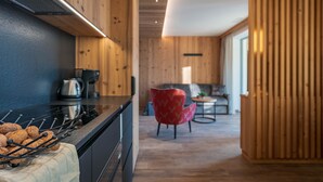 A modern kitchen with wooden walls, a black countertop, and a red chair in the background.