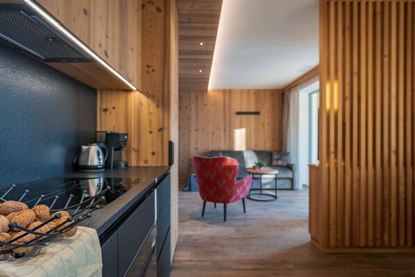 Eine moderne Küche mit Holzwänden, einer schwarzen Arbeitsplatte und einem roten Stuhl im Hintergrund.