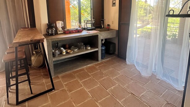 Una cocina con una mesa de madera, una estufa a gas y un ventanal con vistas al verdor.