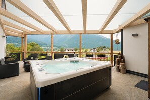 Un bain à remous situé dans un espace extérieur abrité, avec vue sur les montagnes.