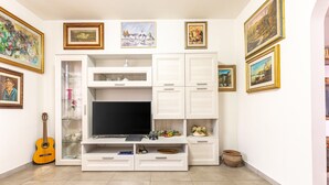 Una sala de estar con televisor, estanterías, una guitarra y cuadros en las paredes.