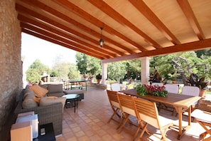 Un patio al aire libre con un área de estar techada, una mesa y sillas.
