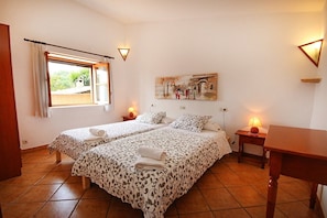 Habitación de hotel con dos camas, un cuadro en la pared, una ventana con cortinas y una mesa de madera.