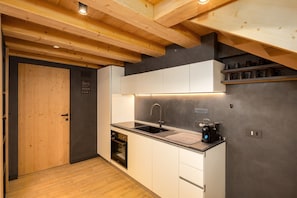 Une cuisine moderne avec des poutres en bois, un évier noir et une machine à café.