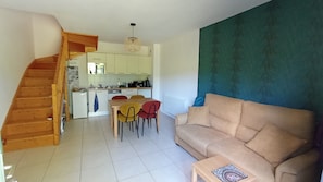 Um espaço de estar moderno com escadas, cozinha, sala de jantar e sofá.