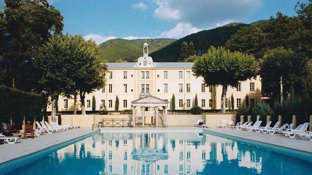 A swimming pool with lounge chairs, a gazebo, and a building with a bell tower. - Château des Gipières, exceptional apartment: Private Garden, Pool, View of Mont Ventoux (Montbrun-les-Bains)