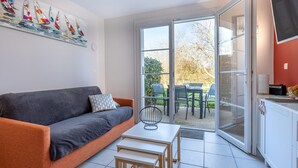 Una sala de estar moderna con un sofá, una mesita y un ventanal corredera que da a un patio exterior.