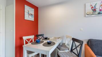 Een eetruimte met een witte tafel, zwarte stoelen en een rode accentmuur.