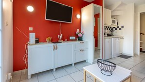 Una cocina moderna con armarios blancos, un televisor de pantalla plana y una zona de comedor con una mesa y sillas.