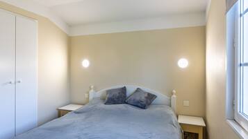 A bedroom with a bed, two bedside tables, a wardrobe, and a window.