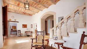 A spacious living room with a wooden staircase, a dining area with a table and chairs, and a view of the kitchen. - Country House 'Magdalena - Son Gaya' with Private Pool, Wi-Fi and Air Conditioning (Illes Balears)