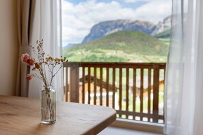 Vista despejada de un paisaje montañoso a través de una ventana con barandilla de madera.