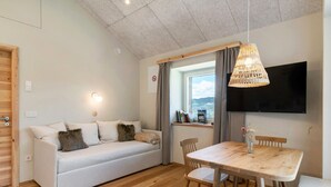 A modern living room with a sofa, dining table, chairs, a TV, and a view of the outdoors. - Apartment 'Hans' with Mountain View, Private Garden and Wi-Fi (Cornedo all'Isarco)