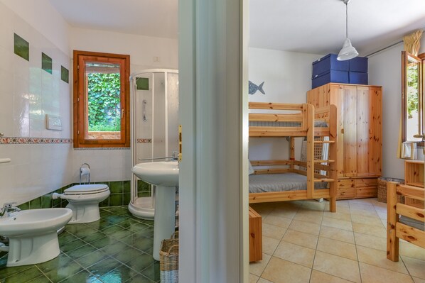 A bathroom with a shower, bidet, and sink.