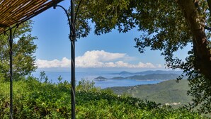 A view of a coastal landscape with a clear sky, lush greenery, and distant mountains. - Villa 'Martini' with Sea View, Private Terrace and Wi-Fi (Marciana)