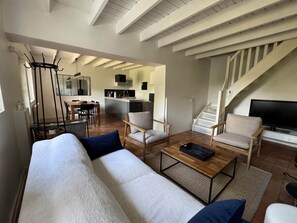 Uma sala de estar moderna com sofá, poltronas, mesa de centro, televisão e escada.