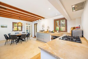 Una cocina moderna con una isla central, un área de comedor con sillas y un ventanal que proporciona luz natural.